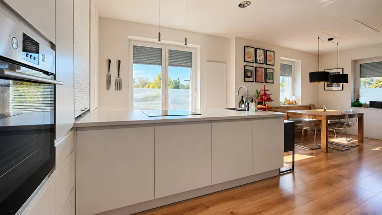 Moderne offene Küche mit Kochinsel und angrenzendem Essbereich, ideal für geselliges Beisammensein.
