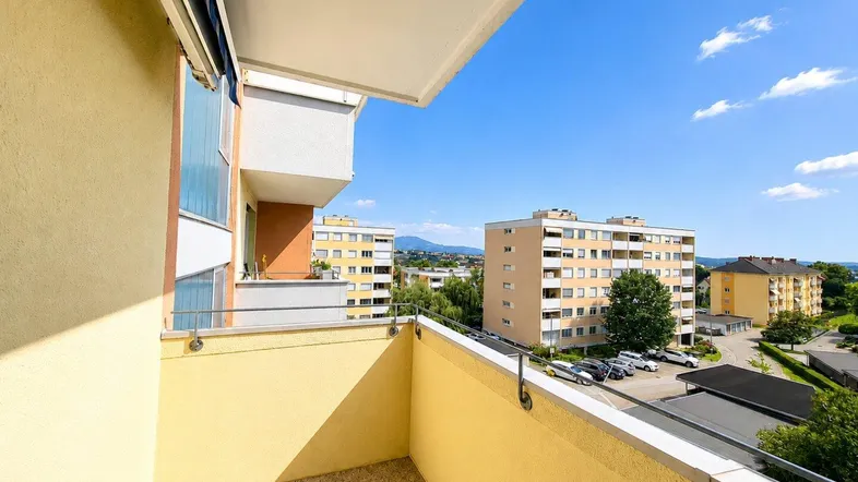 Geräumiger Balkon mit Markise und weitem Blick über die Stadt und die umliegende Landschaft.
