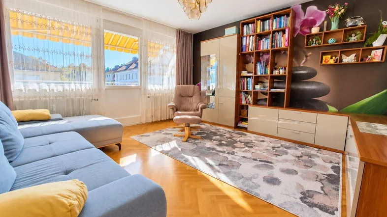 Helles Wohnzimmer mit Parkettboden, großem Bücherregal und Blick auf die Umgebung.