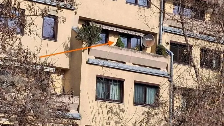 Ein sonniger Balkon mit Pflanzen und einer ausgefahrenen Markise an der Fassade eines Wohngebäudes.