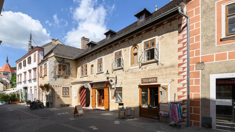 Historische Gebäudezeile in einer charmanten Gasse mit traditioneller Architektur und kleinen Geschäften.