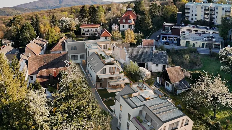 Luftaufnahme einer modernen Wohnanlage in hügeliger Landschaft mit viel Grün und Fernblick.