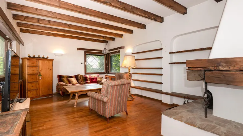 Gemütliches Wohnzimmer mit Holzbalkendecke, Kamin und traditionellen Möbeln, hell und einladend.