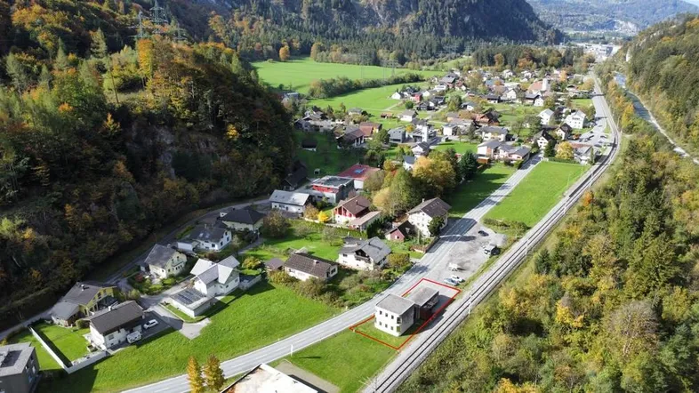 Luftaufnahme eines Dorfes in einer Berglandschaft mit dem markierten Grundstück und umliegender Natur.