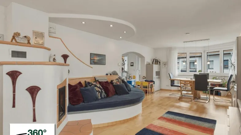 Gemütlicher Wohn-Essbereich mit integriertem Sofa, Kachelofen und hellem Parkettboden.