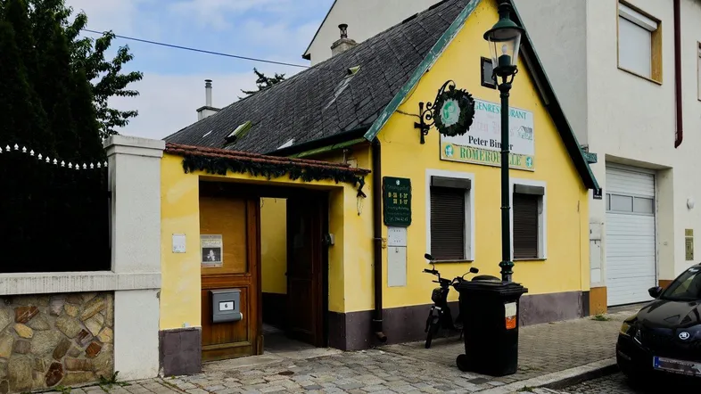 Gelbes Gebäude mit traditioneller Architektur und Satteldach, möglicherweise ein Gasthaus an der Straße.