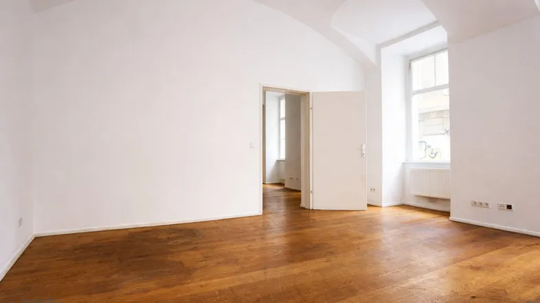 Heller Raum mit Holzboden, weißen Wänden und gewölbter Decke, ideal als Wohn- oder Arbeitsbereich.