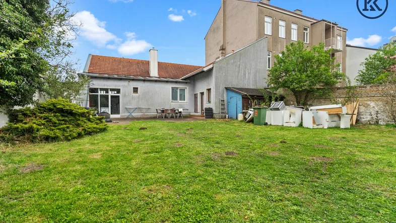 Großer Gartenbereich hinter dem Haus mit Rasenfläche und einer kleinen Terrasse für Outdoor-Aktivitäten.