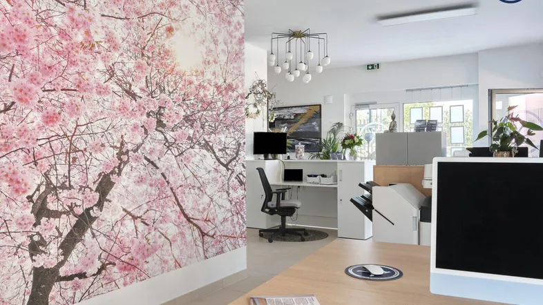 Moderner Bürobereich mit Empfangstheke, Kirschblüten-Tapete und viel Tageslicht.