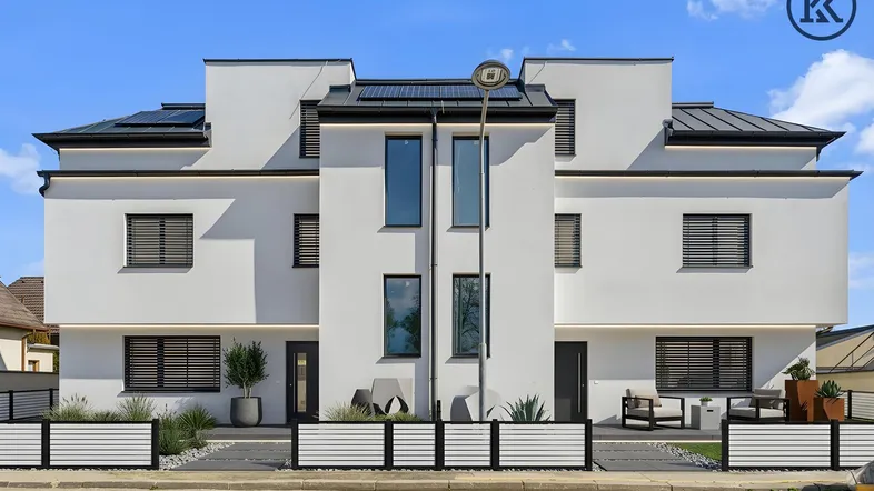 Moderne Doppelhaushälfte mit weißer Fassade, großen Fenstern und gepflegtem Vorgarten.