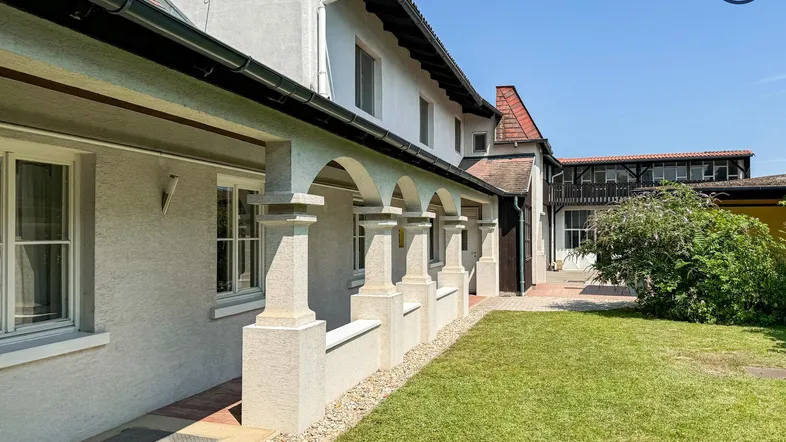 Vorderansicht des Hauses mit gepflegtem Rasen und einer überdachten Veranda mit Säulen.