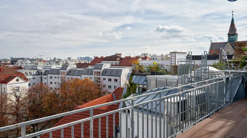 Große Dachterrasse mit Holzboden und Metallgeländer bietet einen weiten Blick über die Stadt.