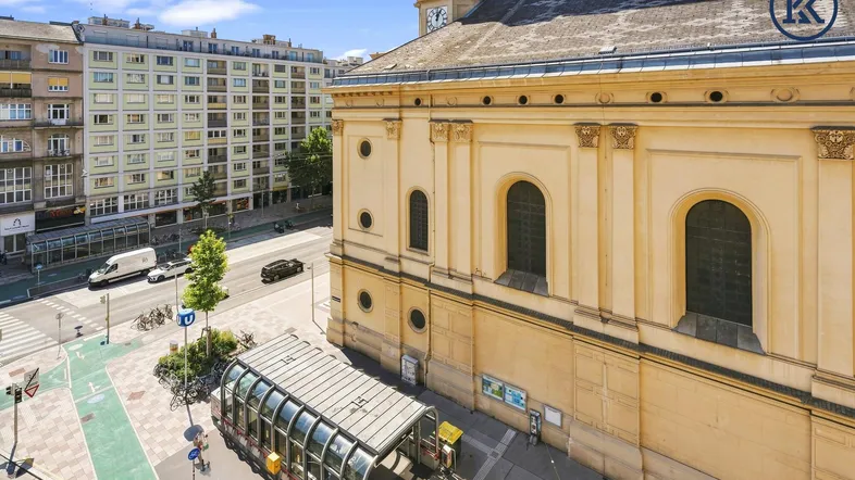 Blick von oben auf eine belebte Straße, eine Kirche und einen U-Bahn-Eingang in der Stadt.