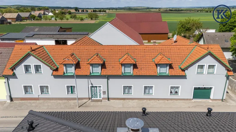 Ansicht des Hauses mit Satteldach und Gaubenfenstern, umgeben von ländlicher Landschaft.