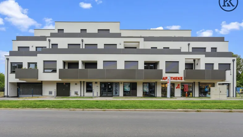 Modernes Mehrfamilienhaus mit Geschäften im Erdgeschoss und Balkonen an der Fassade.