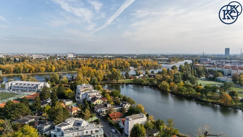 Panoramablick auf eine Stadtlandschaft mit Fluss, Seen und umliegenden Gebäuden unter blauem Himmel.
