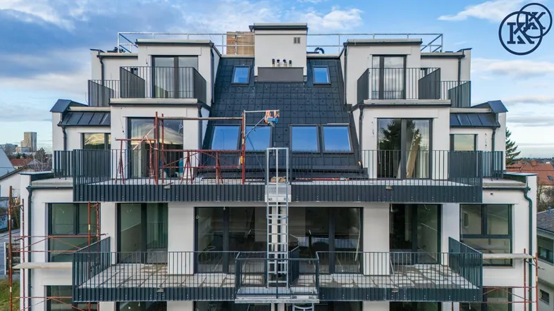 Moderne Wohnanlage im Bau mit mehreren Balkonen und Dachfenstern.