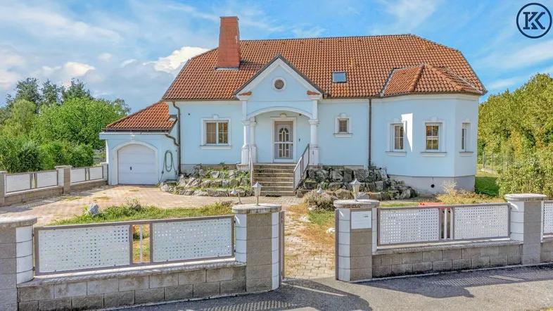 Charmantes Einfamilienhaus mit hellblauer Fassade, rotem Ziegeldach und gepflasterter Auffahrt.
