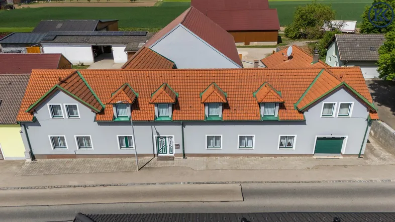 Luftaufnahme eines Wohnhauses mit rotem Ziegeldach und mehreren Gauben in ländlicher Umgebung.