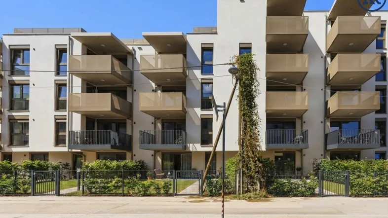 Moderne Wohnanlage mit mehreren Balkonen und gepflegter Grünfläche vor dem Gebäude.