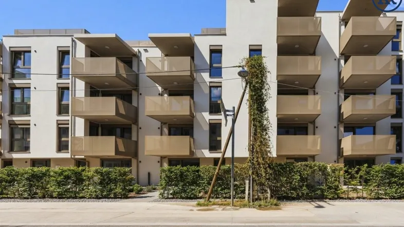 Moderne Wohnanlage mit mehreren Balkonen und gepflegter Grünanlage vor der Fassade.
