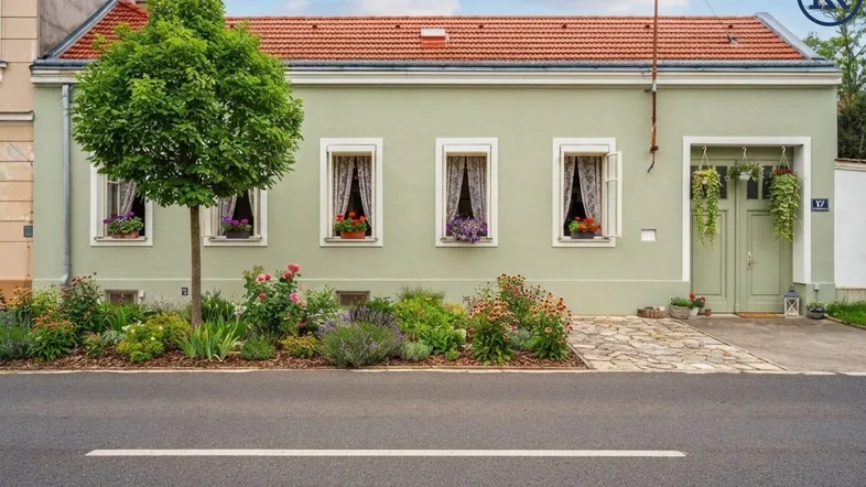 Charmantes Einfamilienhaus mit hellgrüner Fassade, roten Dachziegeln und gepflegtem Vorgarten.