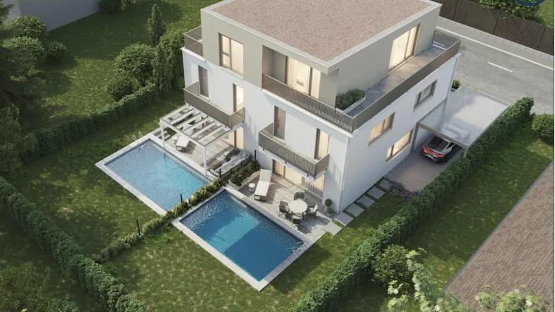 Moderne Villa mit Flachdach, zwei Pools und großzügigem Gartenbereich, umgeben von grüner Landschaft.