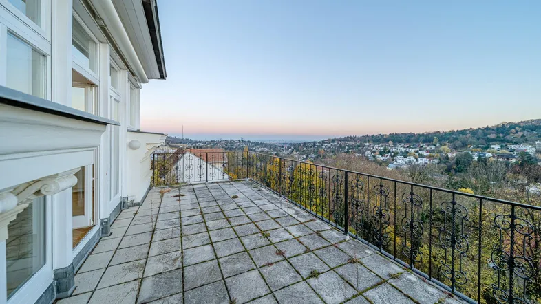 Geräumiger Balkon mit Fliesenboden und schmiedeeisernem Geländer, bietet einen weiten Blick über die Stadt und die Landschaft.