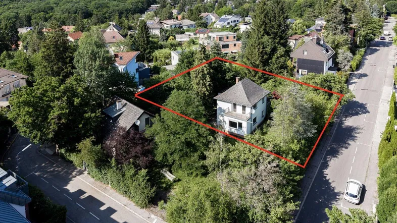 Luftaufnahme eines Hauses mit großem Grundstück, umgeben von Bäumen und einer Wohnsiedlung.