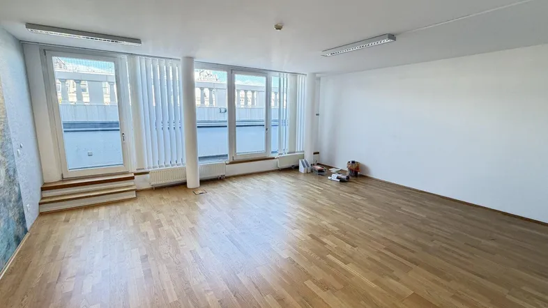 Großer, heller Raum mit Holzboden und Zugang zu einer Terrasse, ideal für Büronutzung.