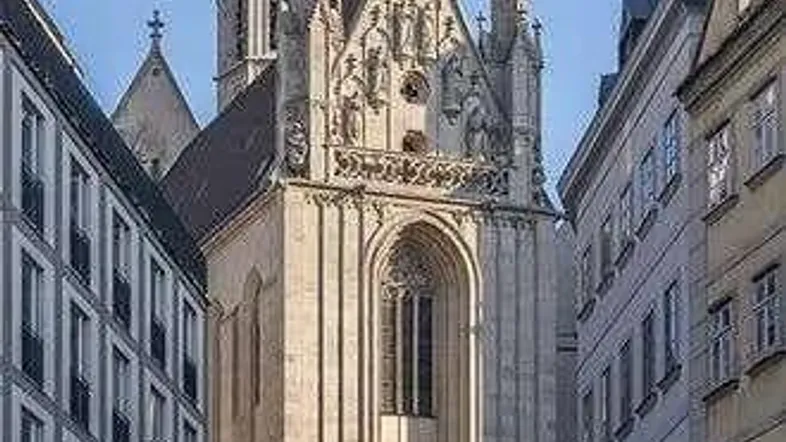 Historisches Kirchengebäude mit aufwendiger Architektur und hohem Turm, umgeben von städtischen Gebäuden.