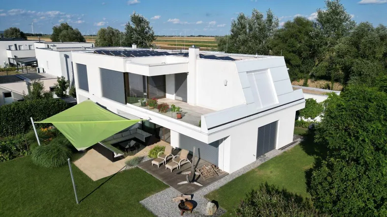 Modernes Einfamilienhaus mit großem Garten, Sonnenterrasse und Photovoltaikanlage auf dem Dach.