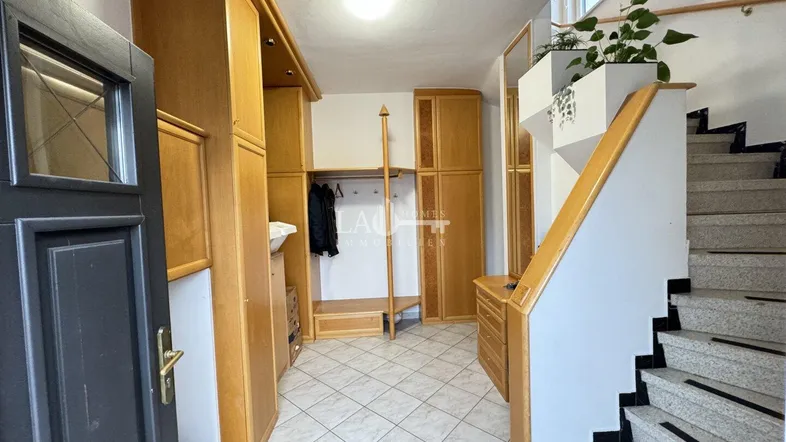 Geräumiger Eingangsbereich mit Einbauschränken aus Holz und Treppenaufgang zum Obergeschoss.