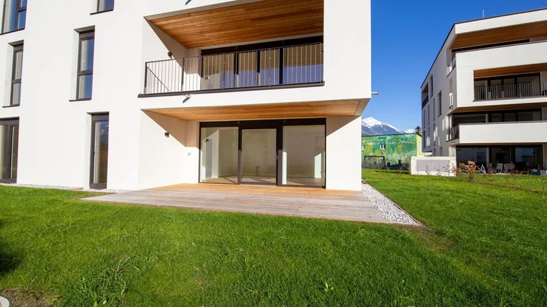 Moderne Wohnanlage mit Terrasse, Balkon, Rasenfläche und Bergblick in sonniger Lage.