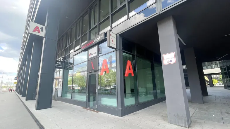 Modernes Geschäftsgebäude mit großer Glasfassade und A1-Logo an der Ecke, gut sichtbar von der Straße.