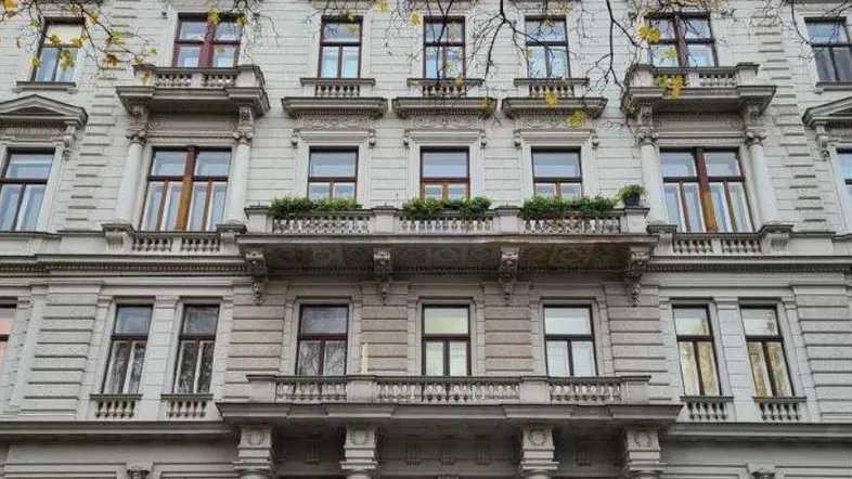 Elegantes Altbaugebäude mit klassischer Fassade, vielen Fenstern und verzierten Balkonen in städtischer Umgebung.