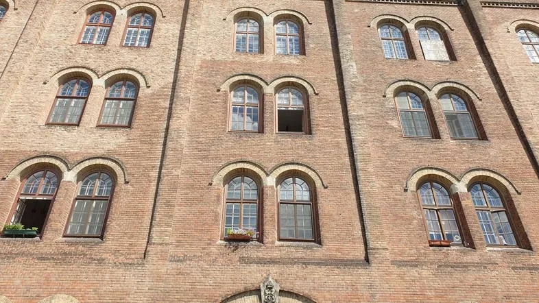 Historische Backsteinfassade mit vielen Rundbogenfenstern und traditioneller Architektur, die den Charme des alten Gebäudes unterstreicht.