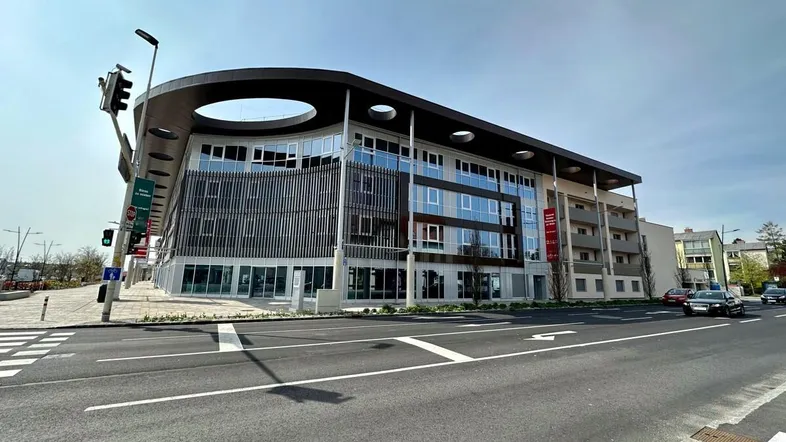 Modernes Geschäftsgebäude mit markanter runder Dachkonstruktion und großen Glasflächen an einer belebten Straße.