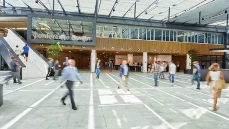 Geräumige, moderne Lobby eines Konferenzzentrums mit viel Tageslicht und Menschen in Bewegung.