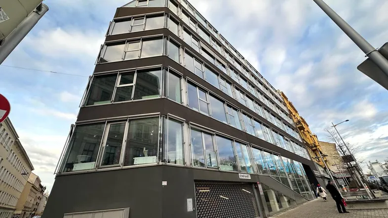 Modernes Gebäude mit markanter Architektur, vielen Fenstern und einer Rollladen-Einfahrt an der Straße.