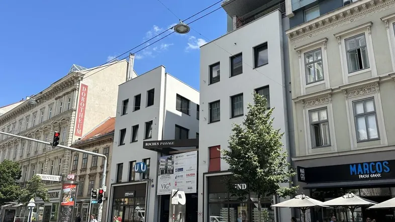 Eine belebte Straße mit modernen und traditionellen Gebäuden unter blauem Himmel.