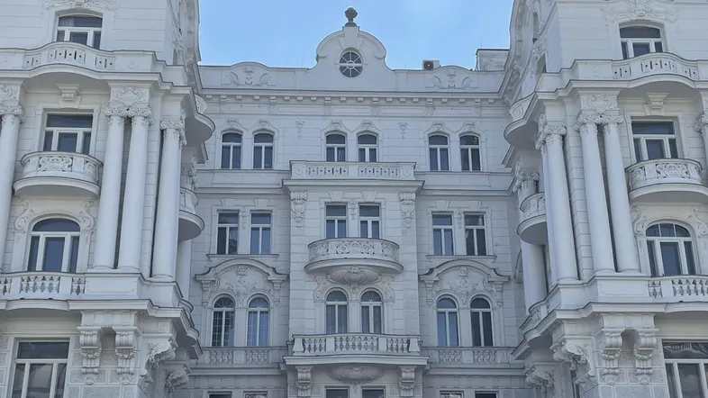 Elegante Fassade eines historischen Gebäudes mit reich verzierten Balkonen und klassischen Säulen.
