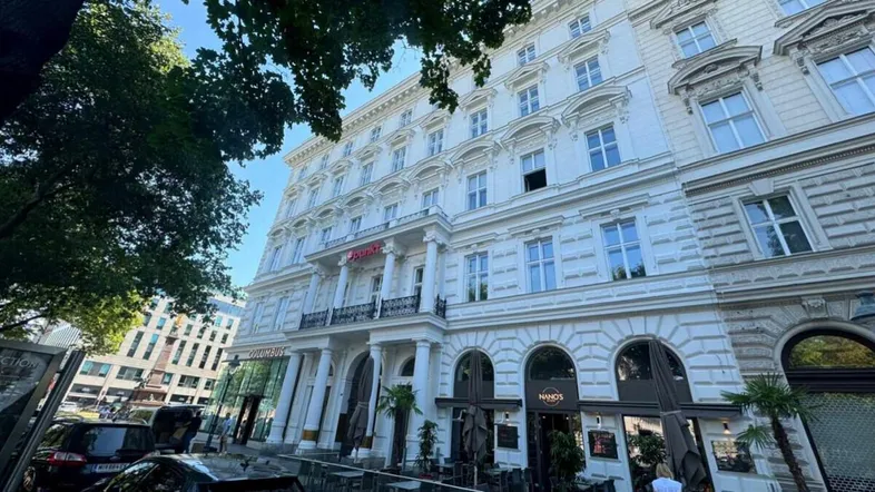 Eindrucksvolles, klassisches Gebäude mit weißer Fassade und Geschäften im Erdgeschoss an einer belebten Straße.