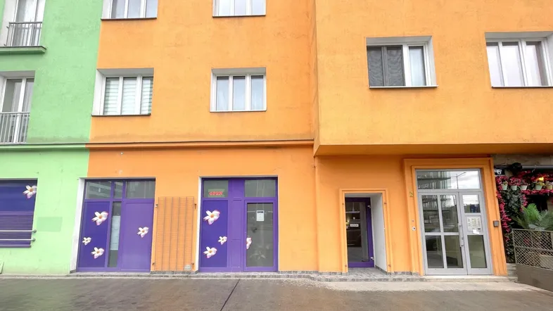 Bunte Fassade eines Gebäudes mit Geschäften im Erdgeschoss und Wohnungen darüber.