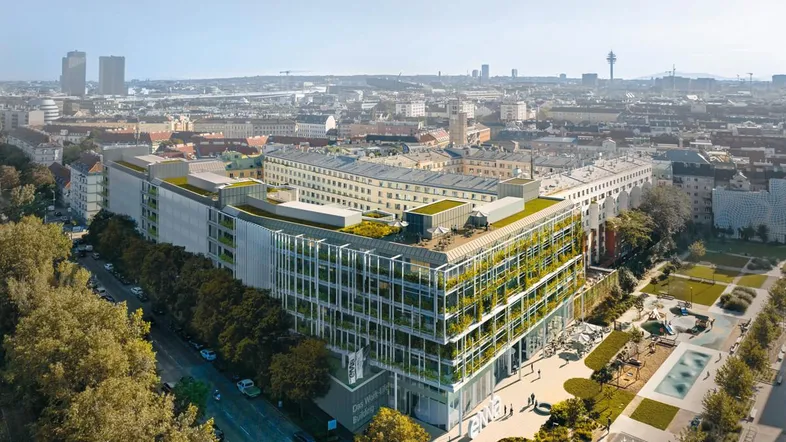 Luftaufnahme eines modernen Gebäudekomplexes mit begrünten Dächern und städtischer Umgebung.
