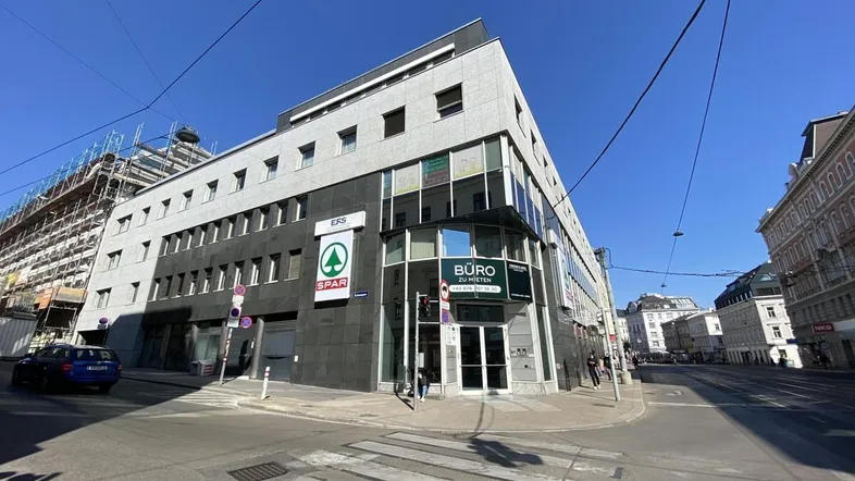 Modernes Geschäftsgebäude an einer Straßenecke mit Einzelhandelsgeschäften im Erdgeschoss und Büros darüber.