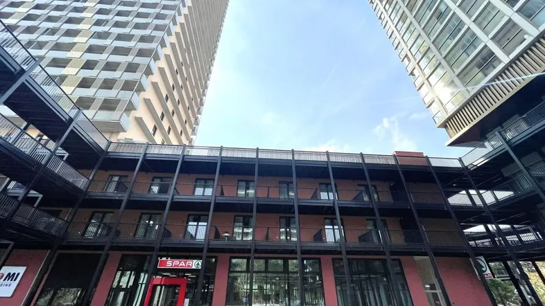 Blick auf die moderne Architektur des Gebäudes mit Einzelhandelsflächen im Erdgeschoss und Wohnungen darüber.
