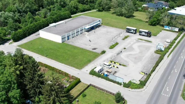 Luftaufnahme eines Gewerbegebäudes mit großem Parkplatz und umliegenden Grünflächen.