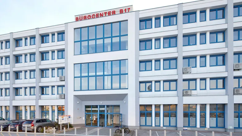 Modernes Bürogebäude mit großen blauen Fenstern und Beschilderung "BÜROCENTER B17" an der Fassade.