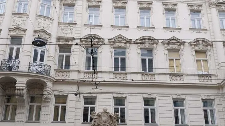 Historisches Gebäude mit klassischer Architektur und verzierten Fassadendetails in einer städtischen Umgebung.